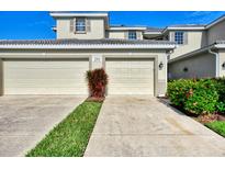 Two-car garage with landscaping and a paved driveway at 3393 Grand Vista Ct # 201, Port Charlotte, FL 33953