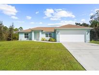 Light blue single-story house with a two-car garage and well-maintained lawn at 7098 Muncey Rd, North Port, FL 34291