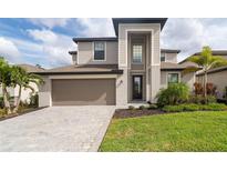 Two-story house with neutral siding, a taupe garage door, and a paved driveway at 19524 Fishhawk Trl, Venice, FL 34293