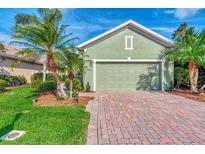 Green house exterior with palm trees, brick driveway, and landscaped lawn at 3155 Osprey Ln, Port Charlotte, FL 33953