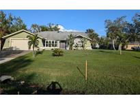 Single story home with green exterior, attached garage, and spacious lawn at 705 Chevy Chase Nw St, Port Charlotte, FL 33948