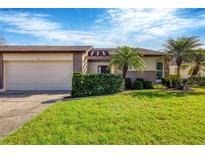 Front view of charming villa with two-car garage, lush landscaping, and attractive curb appeal at 618 Deerwood Ave, Englewood, FL 34223