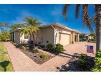 Exterior view of a tan house with a paved walkway, palm trees, and American flag at 13488 Abercrombie Dr, Englewood, FL 34223