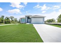 Newly constructed home with a gray exterior, two-car garage, and well-manicured lawn at 147 Ingram Rd, Rotonda West, FL 33947