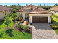 Single-story home with tile roof, landscaping, and a paved driveway at 26790 Weiskopf Dr, Englewood, FL 34223