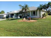 Single-story home with green accents, palm trees, and well-maintained lawn at 3090 Lockwood St, Port Charlotte, FL 33952