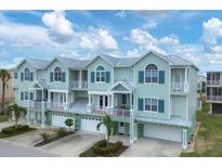 Three-story building with light green exterior, metal roofs, and attached garages at 10390 Longshore Rd # 82, Placida, FL 33946