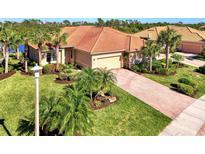 Aerial view of single-story house with tile roof, landscaping, and paved driveway at 13091 Creekside Ln, Port Charlotte, FL 33953