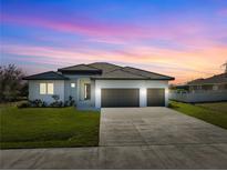 Single-story home with three-car garage, landscaping, and a neutral color palette at 14681 Keystone Blvd, Port Charlotte, FL 33981