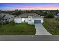 Aerial view of a single-story home with a two-car garage and landscaped lawn at 15384 Hennipen Cir, Port Charlotte, FL 33981