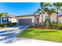 Single-story home with gray garage door, landscaping, and paver driveway at 19584 Fishhawk Trl, Venice, FL 34293