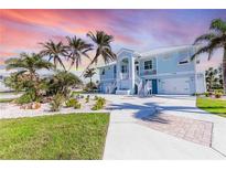 Two-story light blue house with a metal roof, palm trees, and landscaped yard at 13104 Via Cassia, Placida, FL 33946