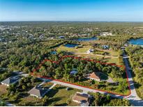 Aerial view of a property nestled amidst lush greenery, showcasing its expansive lot and surrounding neighborhood at 6375 Biggs St, Englewood, FL 34224