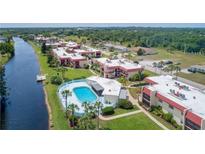 Aerial view of a waterfront community with a pool, lush landscaping, and ample parking at 84 Boundary Blvd # 165, Rotonda West, FL 33947