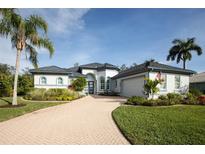 Beautiful one-story home with a tile driveway, lush landscaping, and palm trees at 3030 Rivershore Ln, Port Charlotte, FL 33953