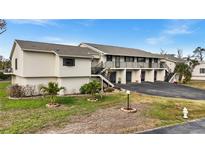 Condo building exterior, featuring multiple units, individual garages, and landscaping at 4260 Placida Rd # 14C, Englewood, FL 34224