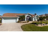 Charming one-story home with a well-manicured lawn, palm trees, and attached garage at 47 Sportsman Ln, Rotonda West, FL 33947