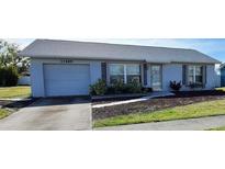 Cute one-story home with gray vinyl siding, attached garage, and nicely landscaped front yard at 13489 Bennett Dr, Port Charlotte, FL 33981