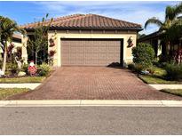 Single-story home with brown garage door and brick paver driveway at 2596 Brassica Dr, North Port, FL 34289