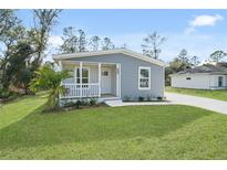 Gray house with white porch and green lawn at 18399 Fremont Ave, Port Charlotte, FL 33954