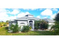 Gray one-story house with a landscaped yard, palm trees, and a screened-in entryway at 328 Baytree Dr, Rotonda West, FL 33947