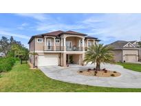 Stunning two-story home boasting a double-door entryway, balcony, and circular driveway with a palm tree feature at 710 Albee W Rd, Nokomis, FL 34275