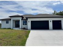 Stunning modern home featuring a two-car garage, lush lawn and a stylish front entrance with a beautiful blue sky at 7330 Printer St, Port Charlotte, FL 33981