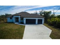 Charming single-story home featuring a two-car garage, well-manicured lawn, and modern architectural details at 7330 Printer St, Port Charlotte, FL 33981