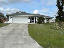 Single-story home with a two-car garage and well-maintained lawn at 872 Dobell Nw Ter, Port Charlotte, FL 33948