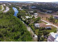 Waterfront property features a pool and lush landscaping along a serene canal leading to the open water at 110 Barracuda Dr, Placida, FL 33946