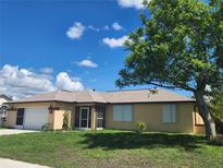 Charming single-story home with a well-manicured lawn and beautiful landscaping and an attached two-car garage at 13278 Carter Ave, Port Charlotte, FL 33981
