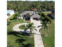 Aerial view of single-story home with circular driveway, landscaping, and waterfront access at 13307 Eisenhower Dr, Port Charlotte, FL 33953