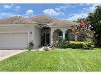 Inviting single-story home featuring a well-manicured lawn, lush landscaping, and a neutral-toned exterior at 13376 Creekside Ln, Port Charlotte, FL 33953