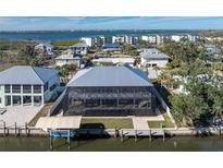 Rear exterior view of home with screened in lanai, boat dock, and waterfront at 9240 Pine Cove Dr, Englewood, FL 34224