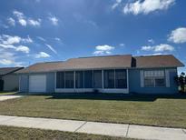 Charming single-story home with a well-maintained lawn and a screened front porch, perfect for enjoying outdoor living at 13537 Bennett Dr, Port Charlotte, FL 33981