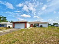 Single story home featuring an attached garage, red trim, and a lawn at 914 E 2Nd St, Englewood, FL 34223