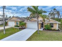 Inviting single-story home with a well-manicured lawn, dual garage, and charming landscaping at 215 Australian Dr, Rotonda West, FL 33947