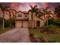 Inviting two-story home with a two-car garage, lush landscaping, and charming curb appeal highlighted by tropical palm trees at 117 Cable Dr, Rotonda West, FL 33947