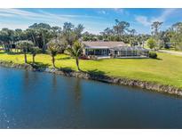 Waterfront home with pool cage and lush landscaping on a sunny day at 891 Harmony Ln, Englewood, FL 34223