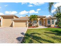 Stunning single-story tan home with a tile roof, arched entryway, attached garage, and beautifully landscaped front yard at 10544 Poughkeepsie Cir, Port Charlotte, FL 33981