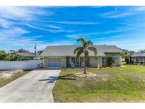 Charming single-story home features a well-manicured lawn, palm tree, and an inviting front porch seating area at 7586 Sea Mist Dr, Port Charlotte, FL 33981