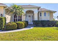 Inviting front entrance with lush landscaping, palm tree, and a charming covered entryway for a warm welcome at 252 Australian Dr, Rotonda West, FL 33947