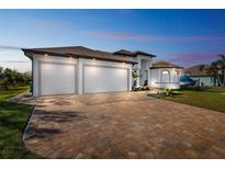 Stunning new home features a brick paver driveway, lush landscaping, and a three-car garage at 9533 Arnaz Cir, Port Charlotte, FL 33981
