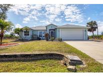 Inviting one-story home featuring a well-manicured lawn, lovely landscaping, and an attached two-car garage at 10307 Grail Ave, Englewood, FL 34224