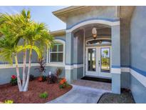 Inviting front entrance with double doors, decorative archway, and lush landscaping at 15610 Seafoam Cir, Port Charlotte, FL 33981