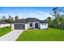 Charming single-story home featuring manicured lawn, a gray roof, and an attached two-car garage at 1664 Jagust Rd, North Port, FL 34288