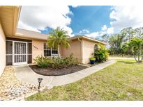 Charming home with well-maintained landscaping, palm trees, and a cozy front porch seating area at 1003 Old Englewood Rd, Englewood, FL 34223