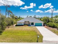 Charming single-story home with a well-manicured lawn and a turquoise garage door at 11453 Oceanspray Blvd, Englewood, FL 34224