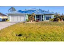 Charming single-story home featuring a large front yard, two-car garage, and light green exterior at 12028 Newgate Ave, Port Charlotte, FL 33981