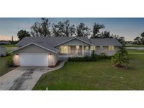 Charming single-story home featuring a well-manicured lawn and inviting covered porch at 18 Pebble Beach Road, Rotonda West, FL 33947